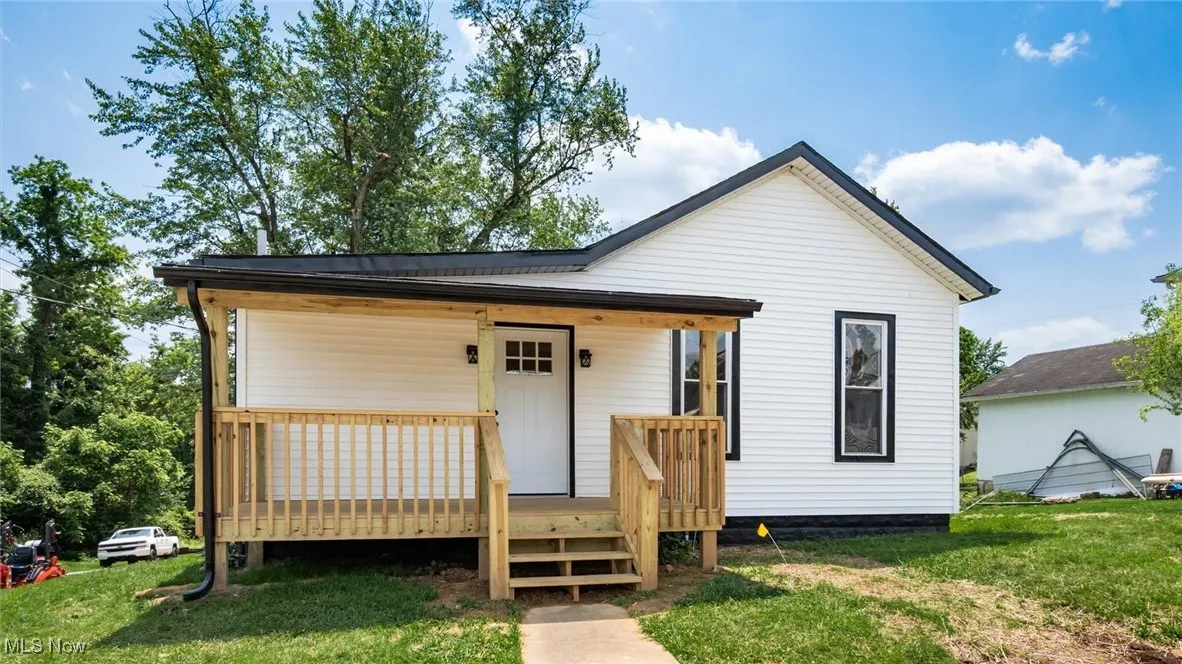 View of front of property with a wooden deck and a front lawn