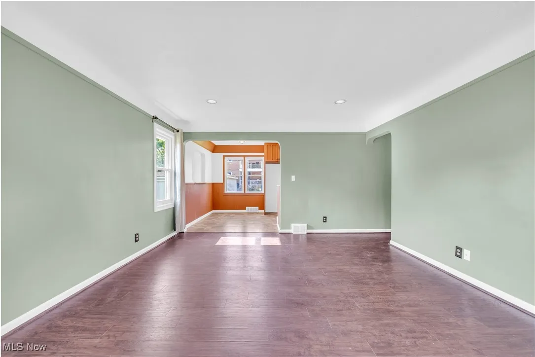 Empty room featuring arched walkways, dark wood-style flooring, and recessed lighting