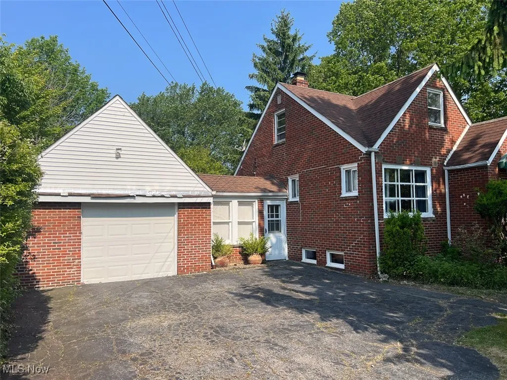 View of home's exterior with a chimney, driveway, a garage, and brick siding