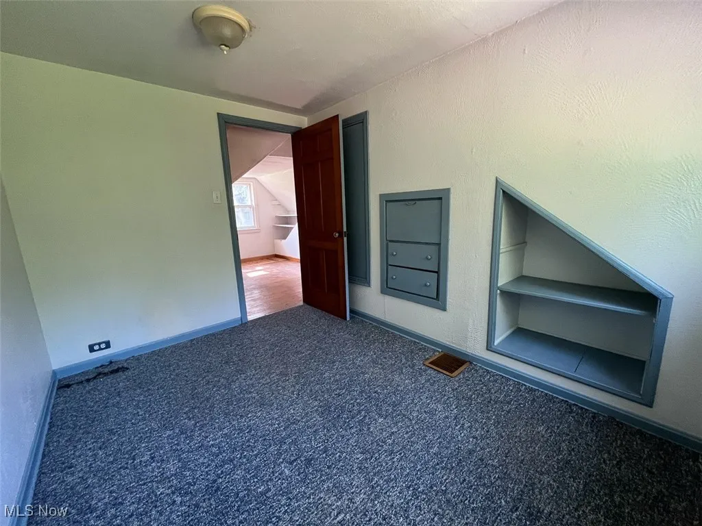 Carpeted spare room featuring built in features and baseboards