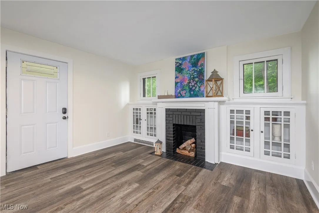 Unfurnished living room with wood finished floors and a brick fireplace