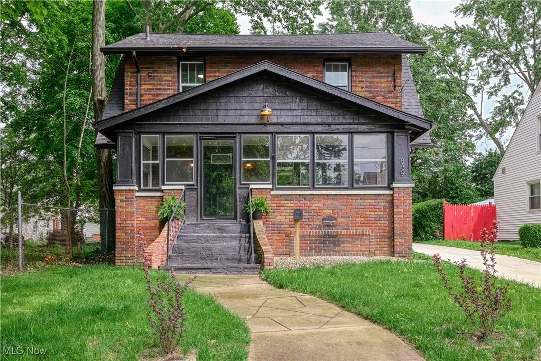 View of front of house featuring a sunroom and brick siding