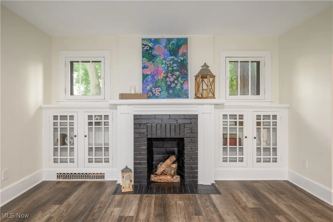 Unfurnished living room featuring wood finished floors and a brick fireplace