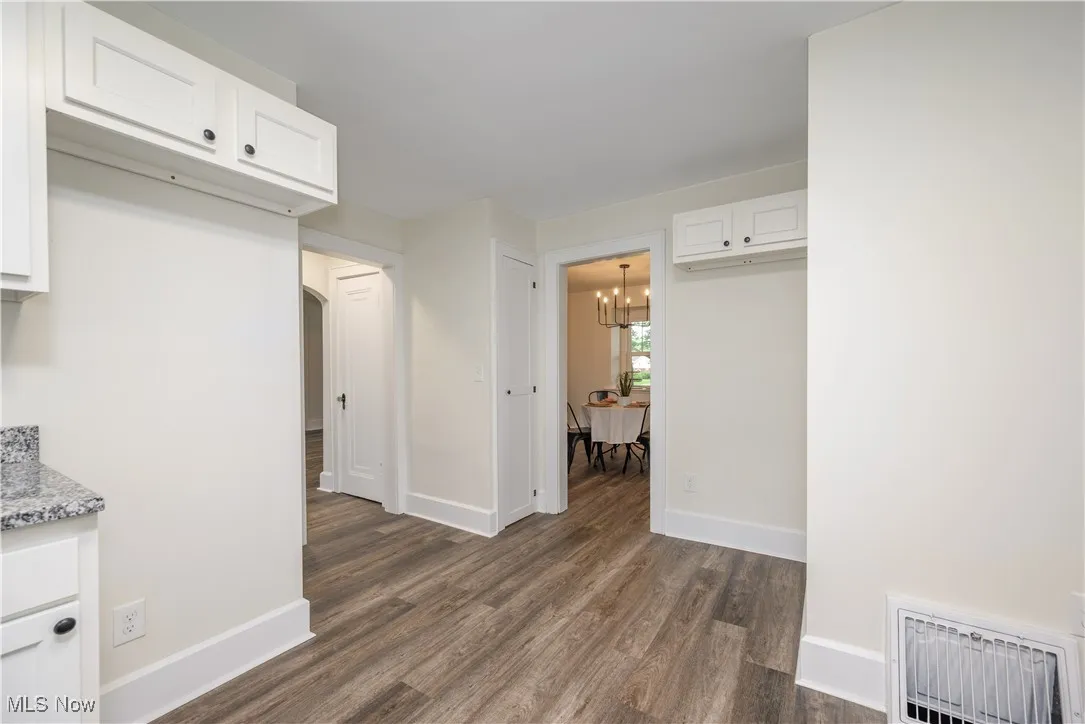 Kitchen featuring
 dark wood-style floors, white cabinets, and light stone countertops