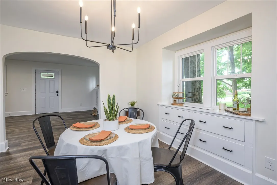 Dining space featuring arched walkways, a chandelier, and dark wood finished floors