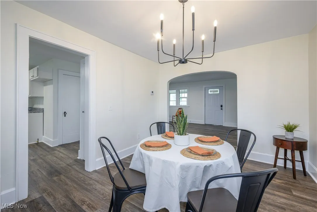 Dining area with arched walkways, dark wood-style floors, and a chandelier