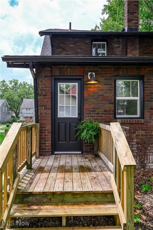 Property entrance featuring brick siding and a wooden deck