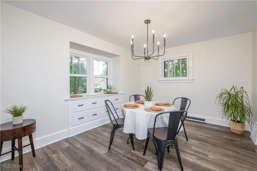 Dining space featuring a chandelier, dark wood-type flooring, and healthy amount of natural light