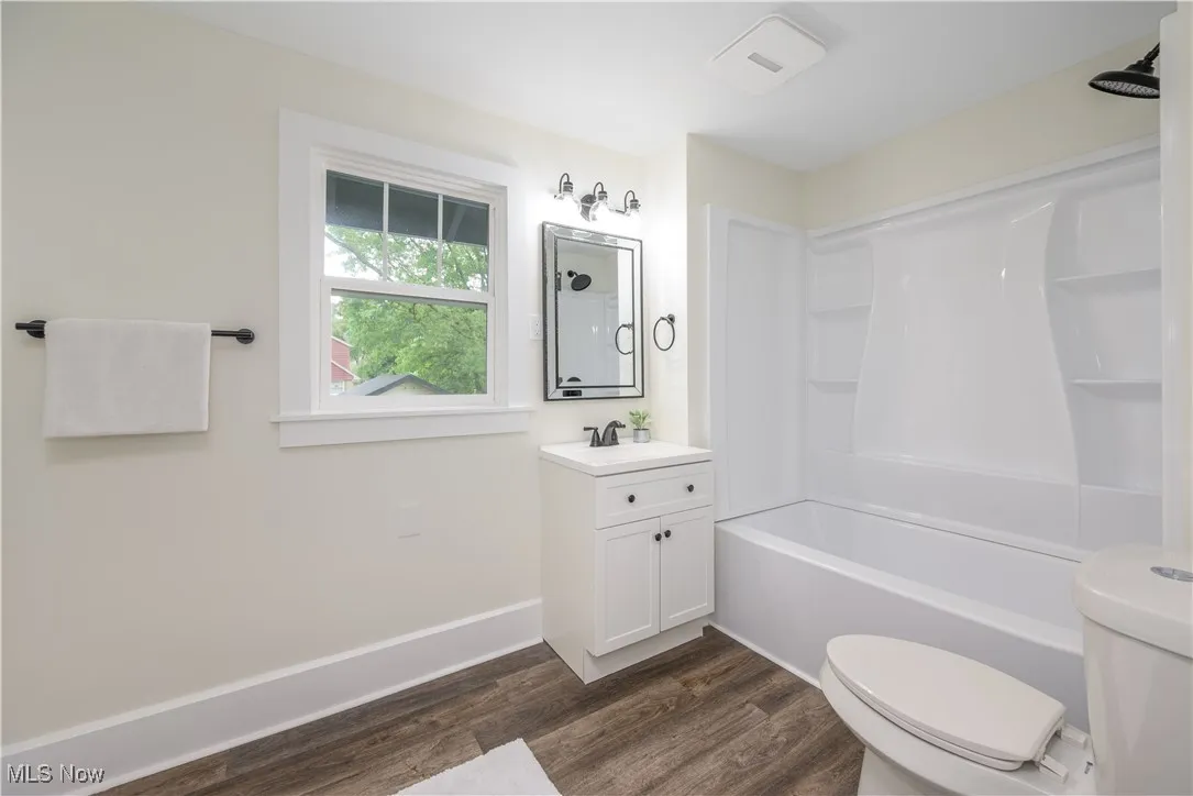 Full bath with wood finished floors, vanity, and washtub / shower combination
