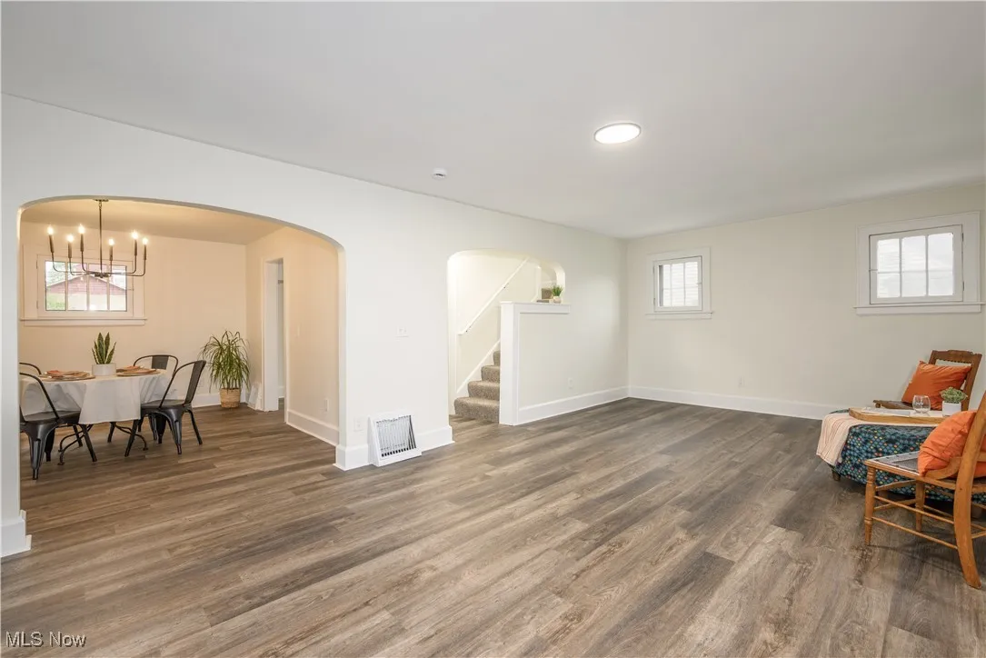 Sitting room with a chandelier, arched walkways, dark wood-type flooring, stairs, and recessed lighting