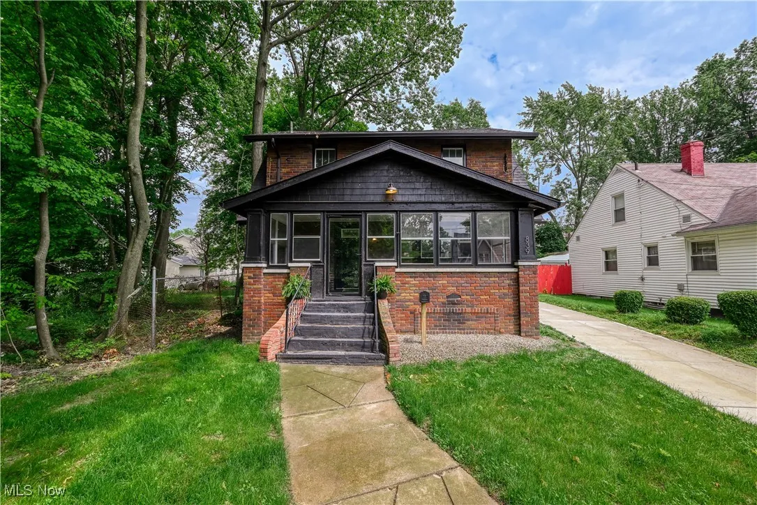 View of front of property with brick siding, a front lawn, and a sunroom