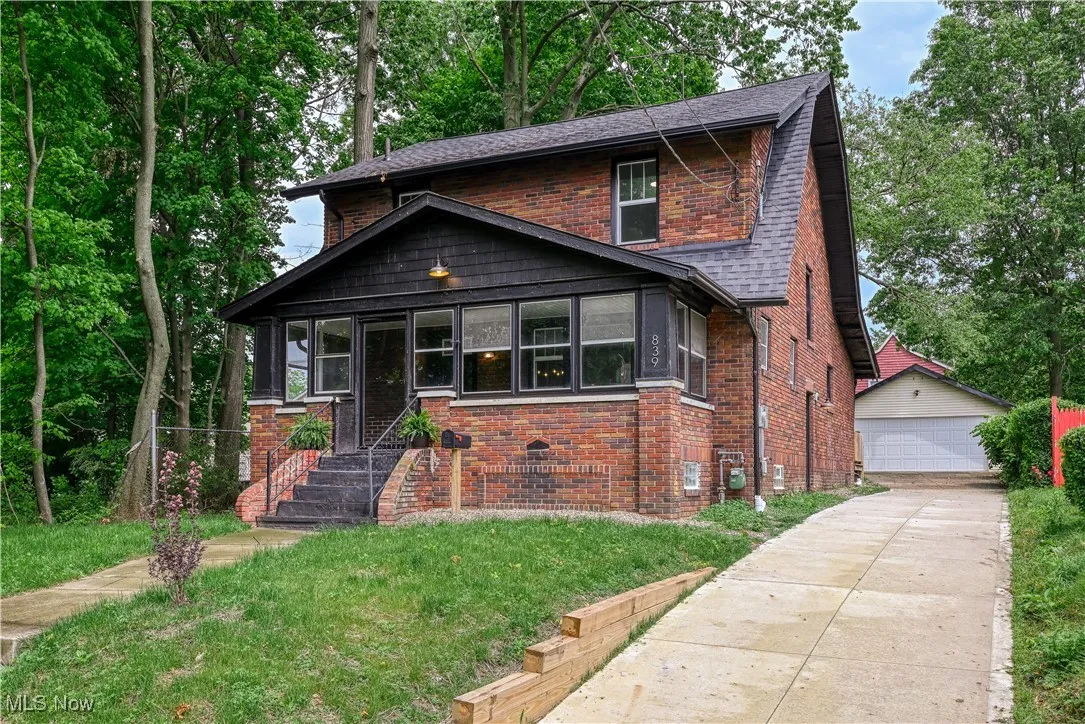 View of front of house featuring a garage, brick siding, a shingled roof, an outdoor structure, and a front yard
