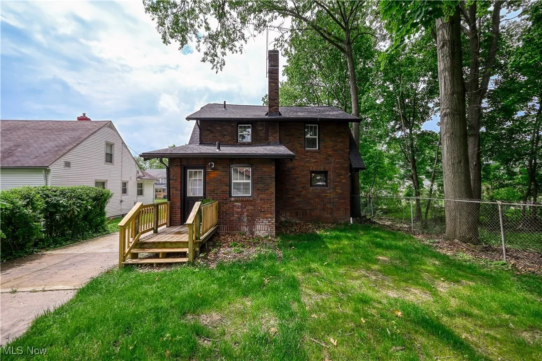 Back of property featuring brick siding, a deck, and a chimney