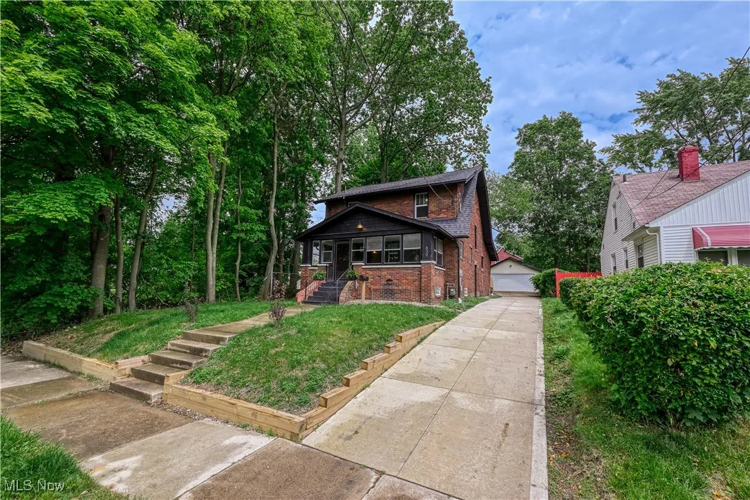 View of front of home with brick siding, an outbuilding, covered porch, and a detached garage