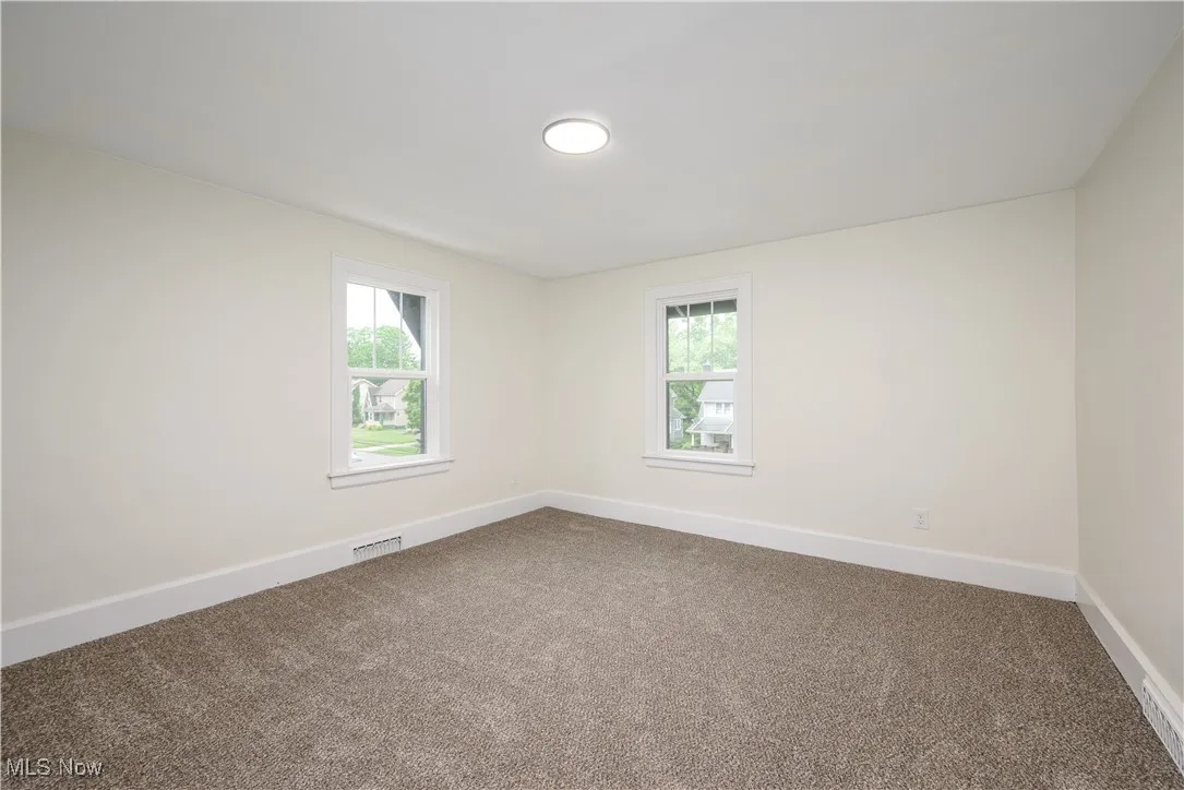 Unfurnished room with dark carpet and healthy amount of natural light