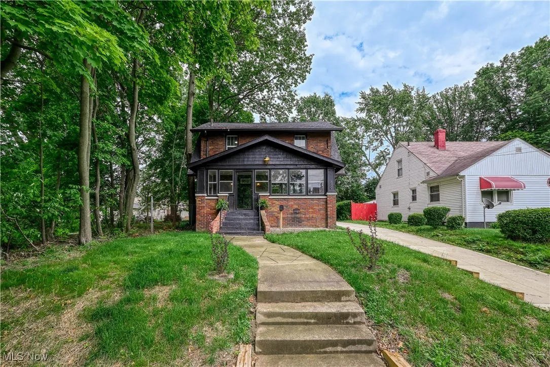 View of front of property with brick siding, a front yard, and covered porch