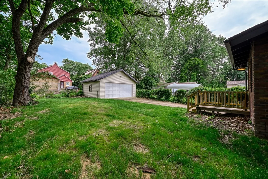 View of grassy yard with an outbuilding, a garage, and a deck