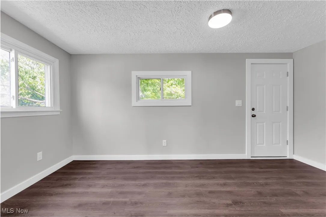 Unfurnished room featuring a textured ceiling, plenty of natural light, and wood finished floors