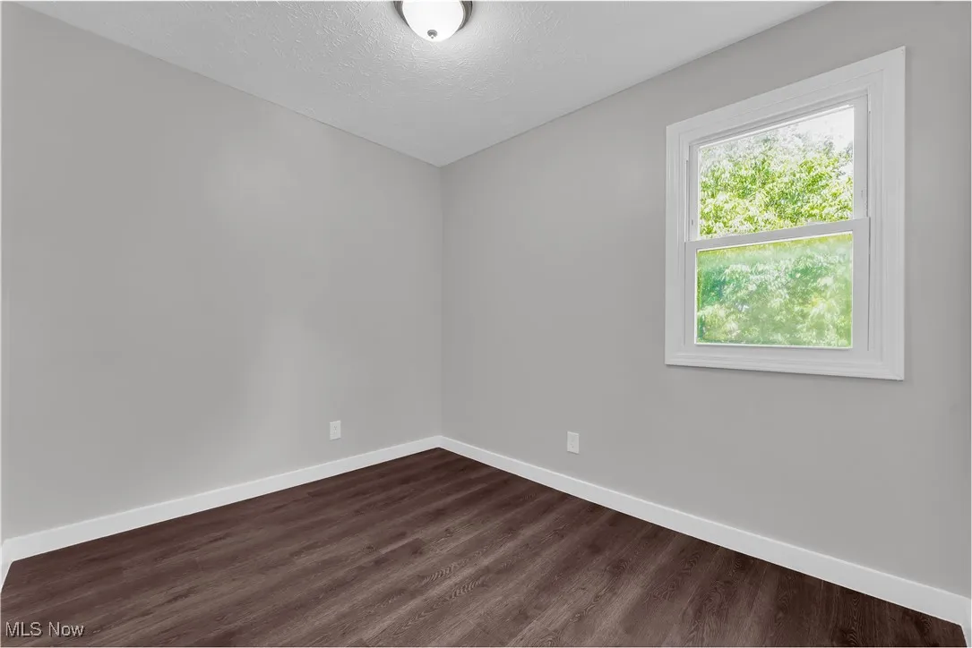 Spare room with dark wood-type flooring and a textured ceiling