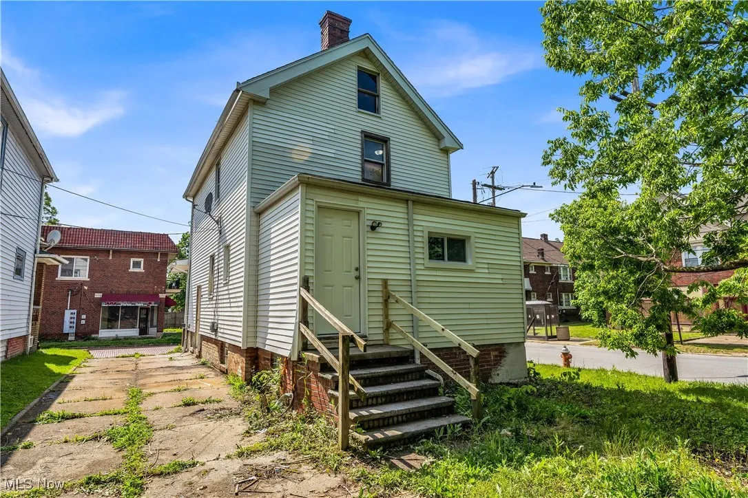 Back of house with entry steps and a chimney