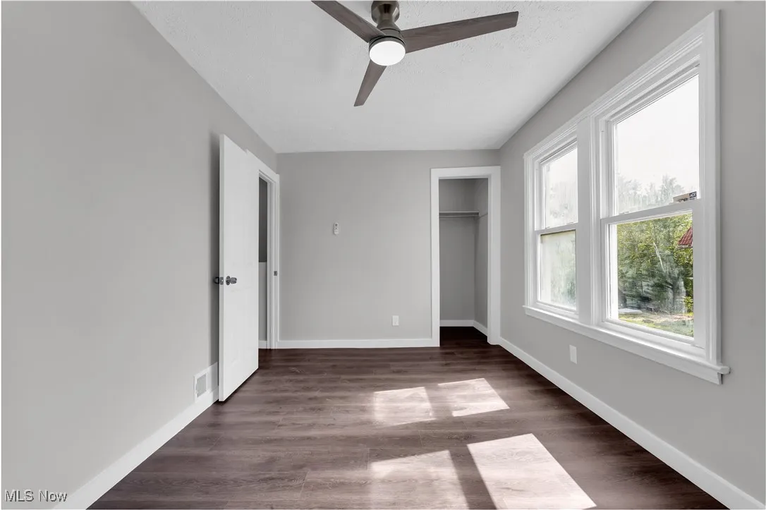Unfurnished bedroom with dark wood-style flooring, a closet, a ceiling fan, and a textured ceiling