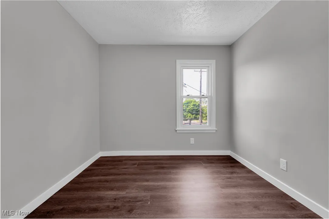 Unfurnished room with a textured ceiling and dark wood-style floors