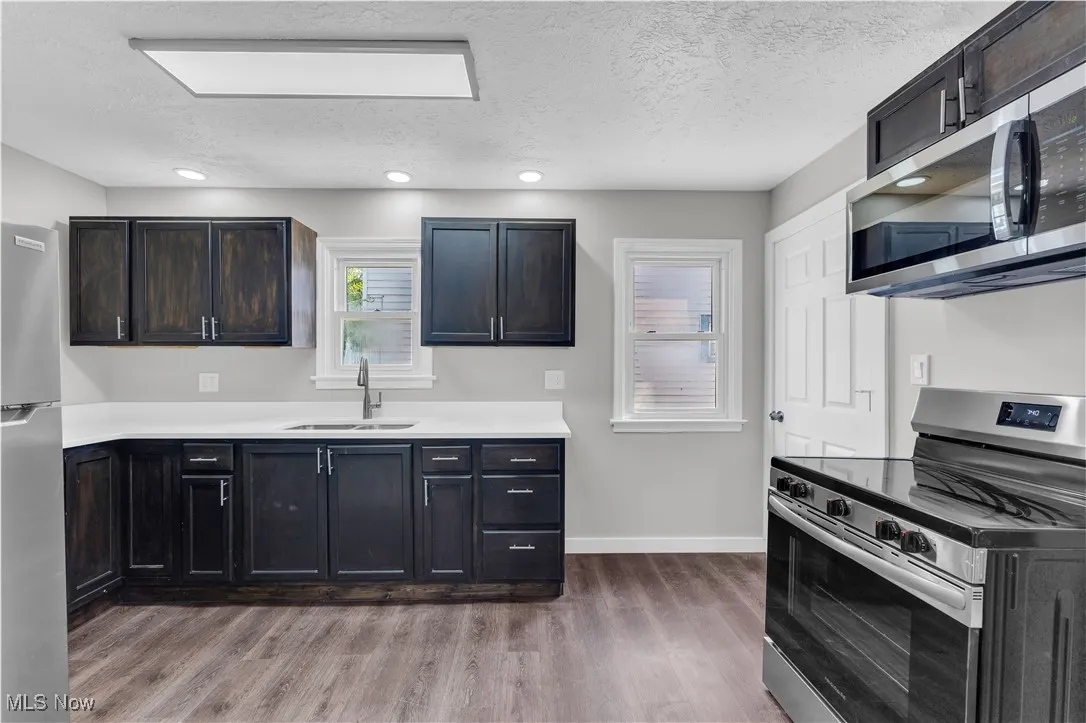 Kitchen featuring appliances with stainless steel finishes, a textured ceiling, dark wood finished floors, light countertops, and recessed lighting