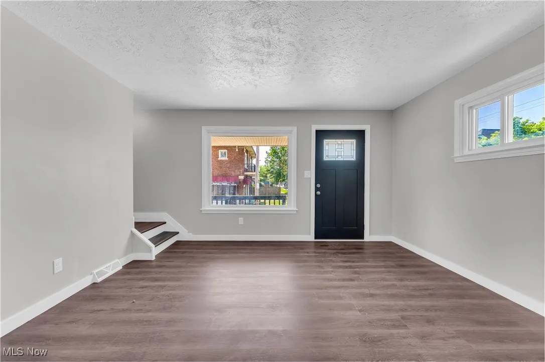 Foyer with a textured ceiling, wood finished floors, and stairs