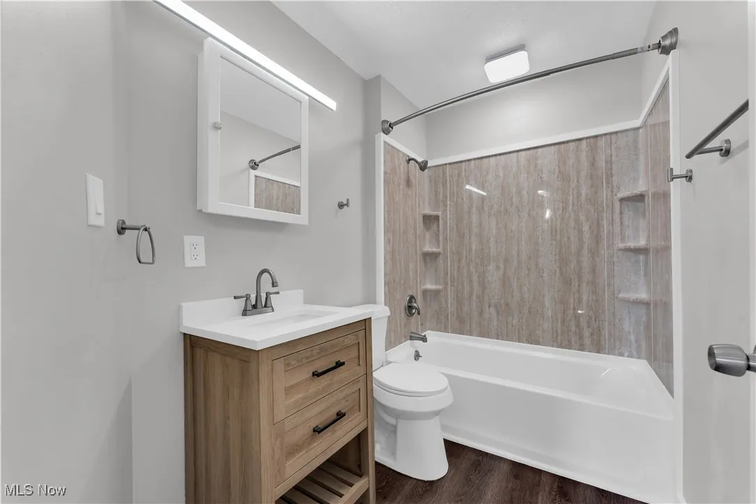 Bathroom featuring vanity, shower / tub combination, and wood finished floors