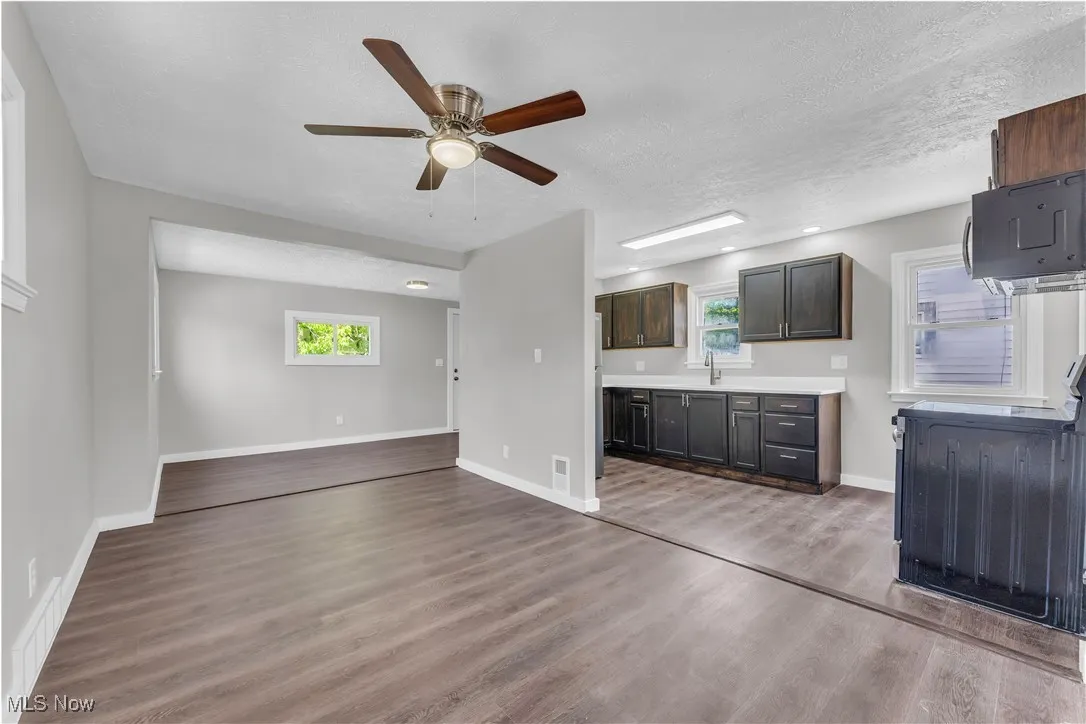 Unfurnished living room with light wood finished floors, a ceiling fan, and a textured ceiling