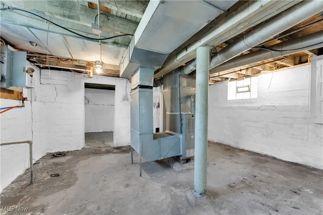 Below grade area with electric panel and heating unit