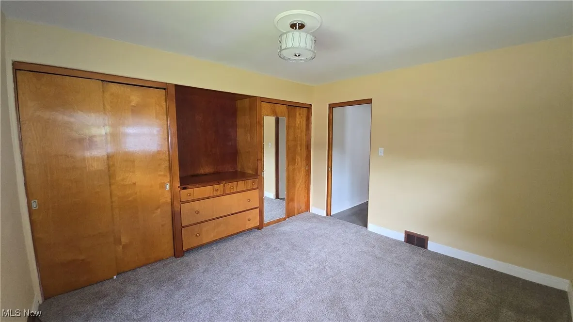 Unfurnished bedroom featuring carpet and baseboards