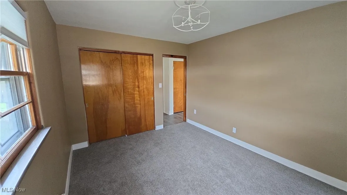 Unfurnished bedroom featuring a chandelier, carpet, and a closet