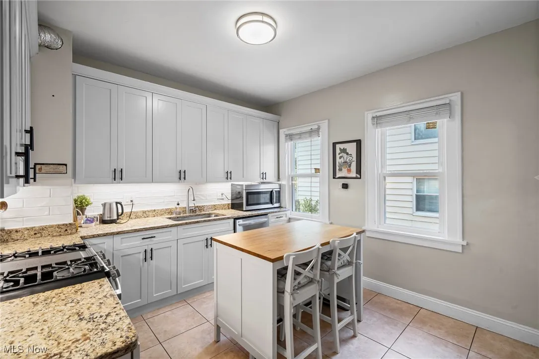 Kitchen featuring stainless steel appliances, light tile patterned floors, wood counters, and decorative backsplash