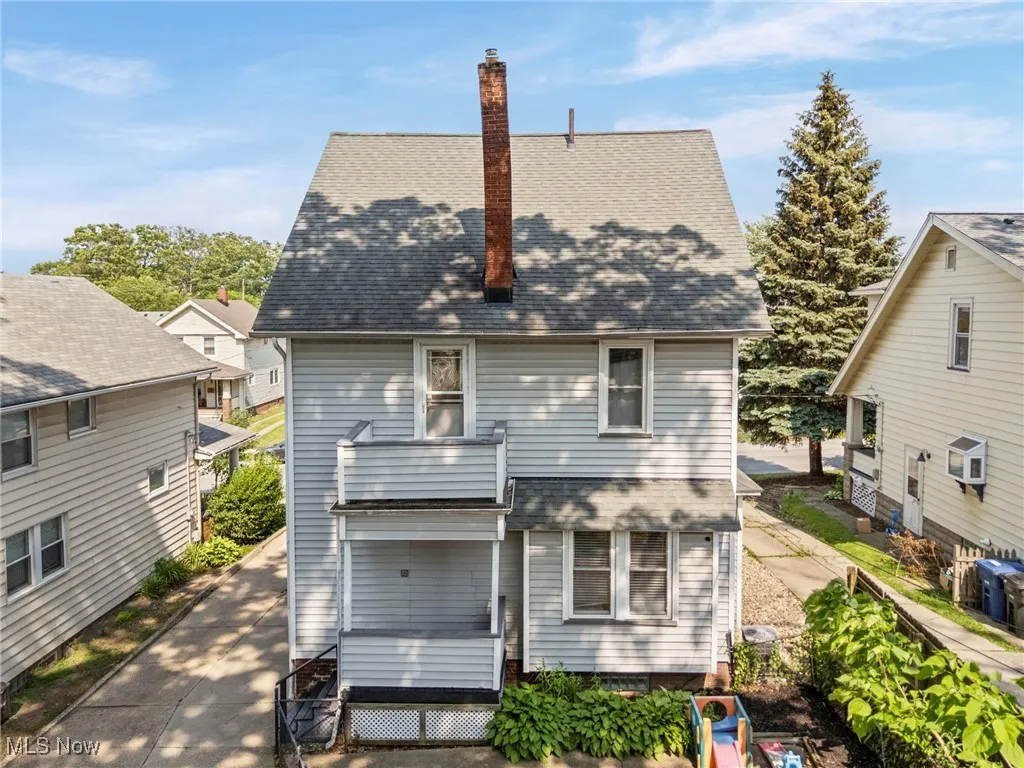 Back of house with a shingled roof and a chimney