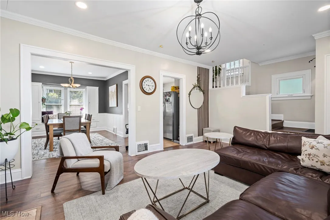 Living room with a chandelier, wood finished floors, plenty of natural light, crown molding, and recessed lighting