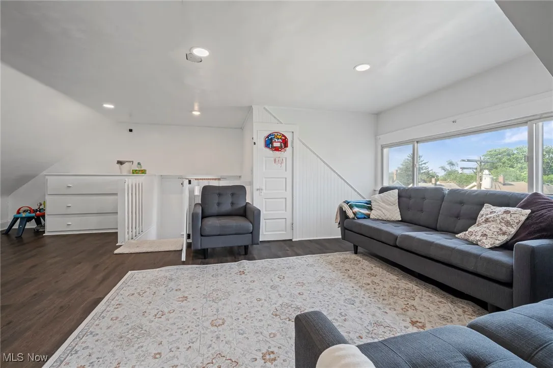 Living room with dark wood finished floors, recessed lighting, and lofted ceiling