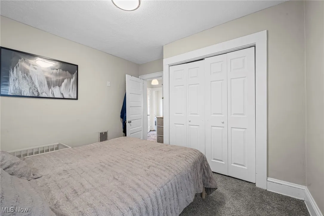Carpeted bedroom with a closet and a textured ceiling