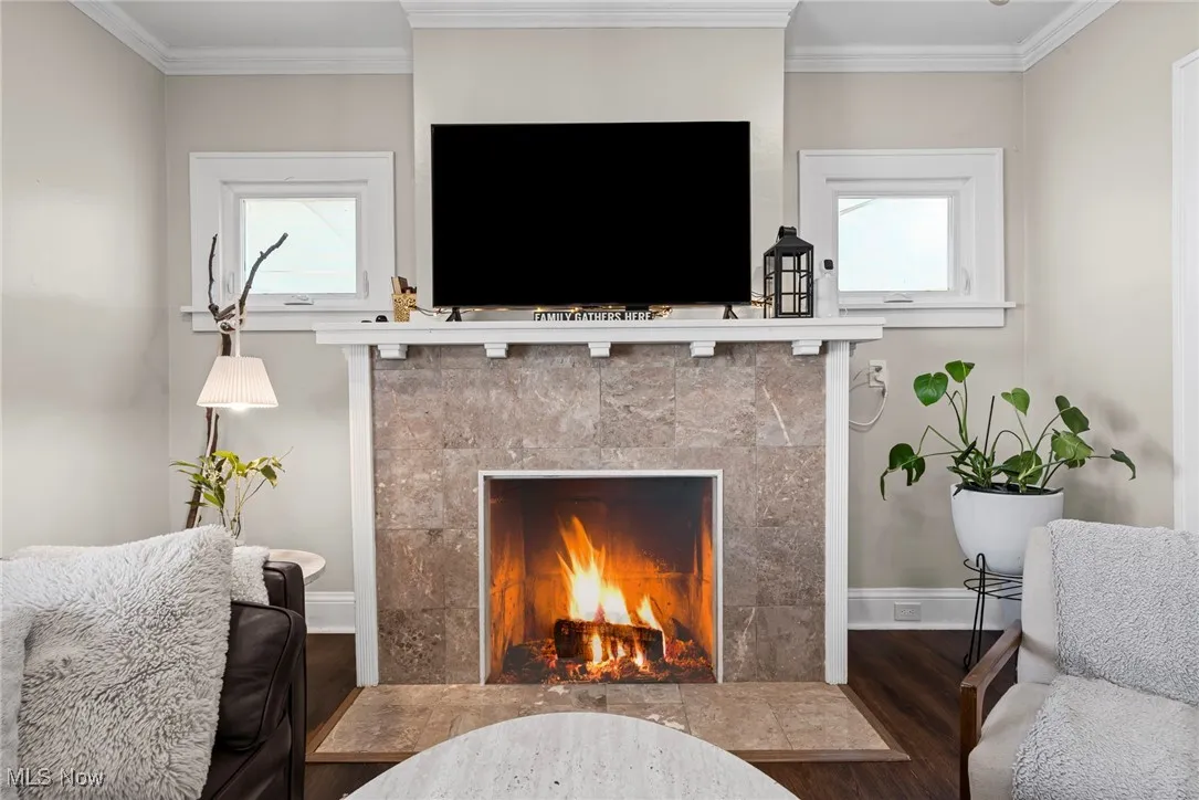 Detailed view of a tile fireplace, wood finished floors, and crown molding