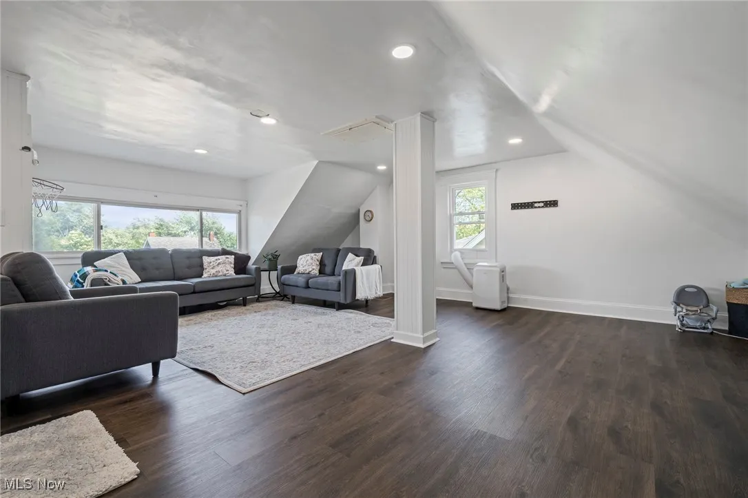 Living area featuring dark wood-style floors, recessed lighting, and vaulted ceiling