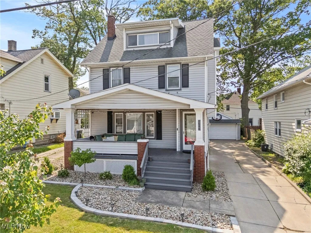 American foursquare style home featuring a porch, an outdoor structure, roof with shingles, a garage, and a chimney