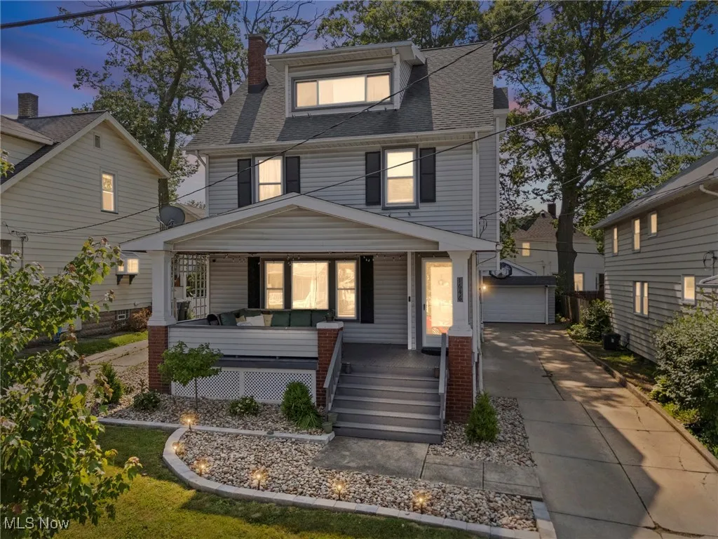 Traditional style home featuring a porch, an outdoor structure, a detached garage, roof with shingles, and a chimney