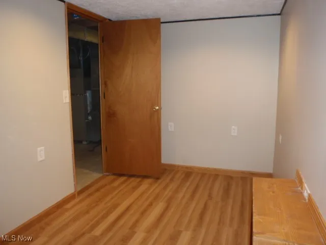 Spare room featuring light wood-style floors and baseboards