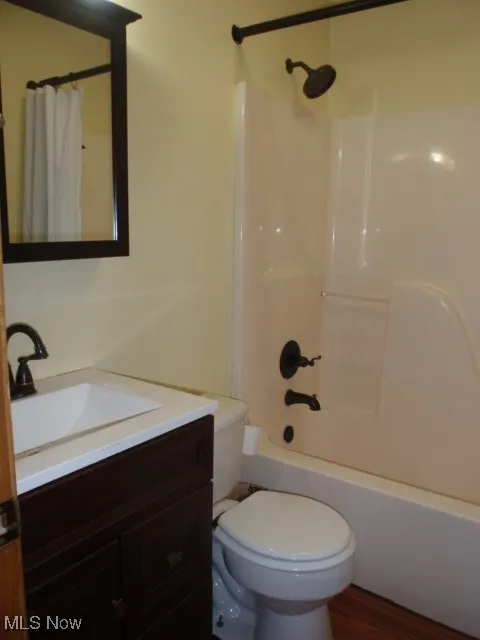 Full bath featuring vanity, shower / bath combination with curtain, and wood finished floors