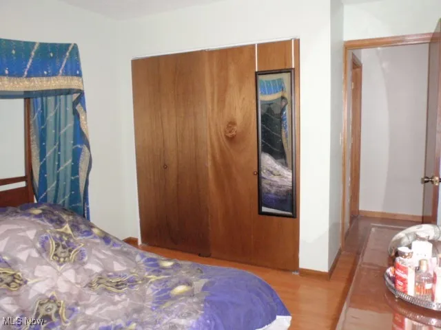 Bedroom with wood finished floors and a closet
