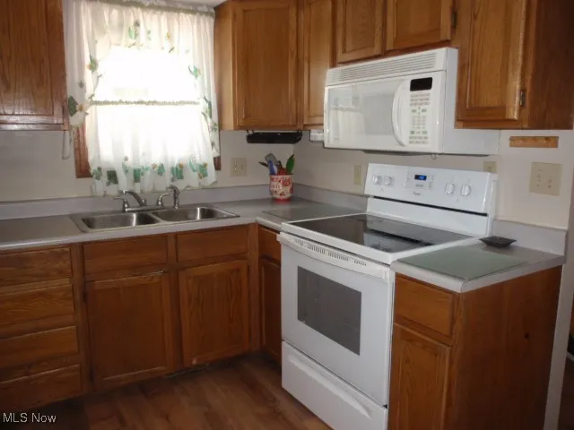 Kitchen featuring white appliances, brown cabinets, and light countertops