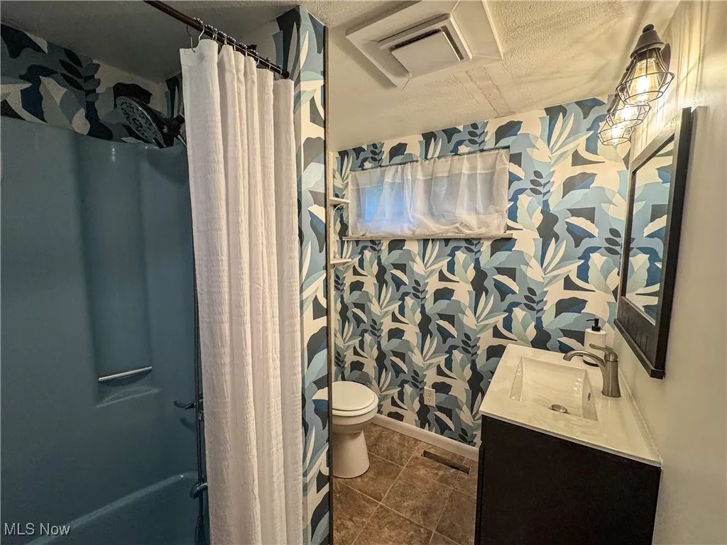 The main bathroom has wallpaper reminescent of mid-century decor.