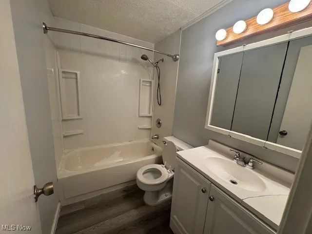 Full bathroom featuring a textured ceiling, wood finished floors, vanity, and shower / washtub combination