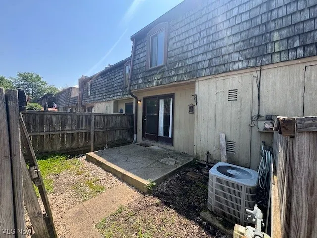 Rear view of house with mansard roof, a fenced backyard, and a patio