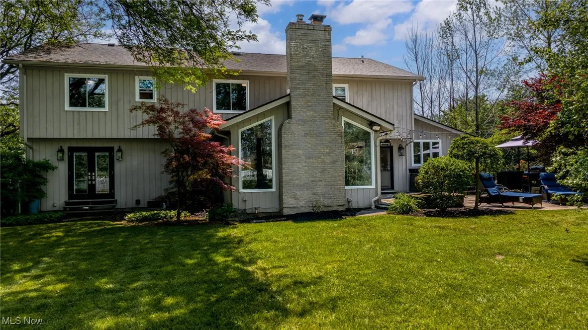Back of property featuring french doors, a chimney, a lawn, and roof with shingles
